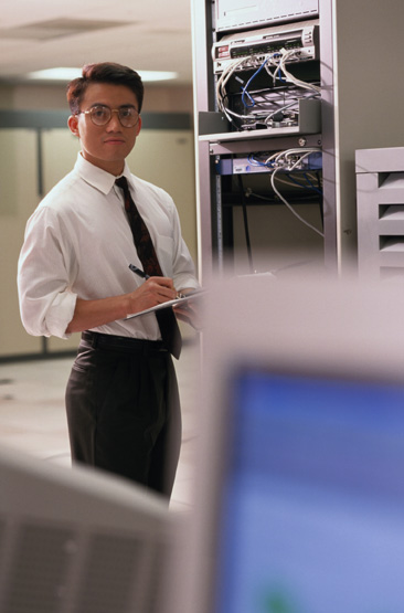 an employee writing notes while working in a computer room.